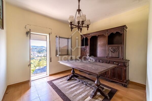 Sala com mesa de madeira, aparador e porta para a varanda